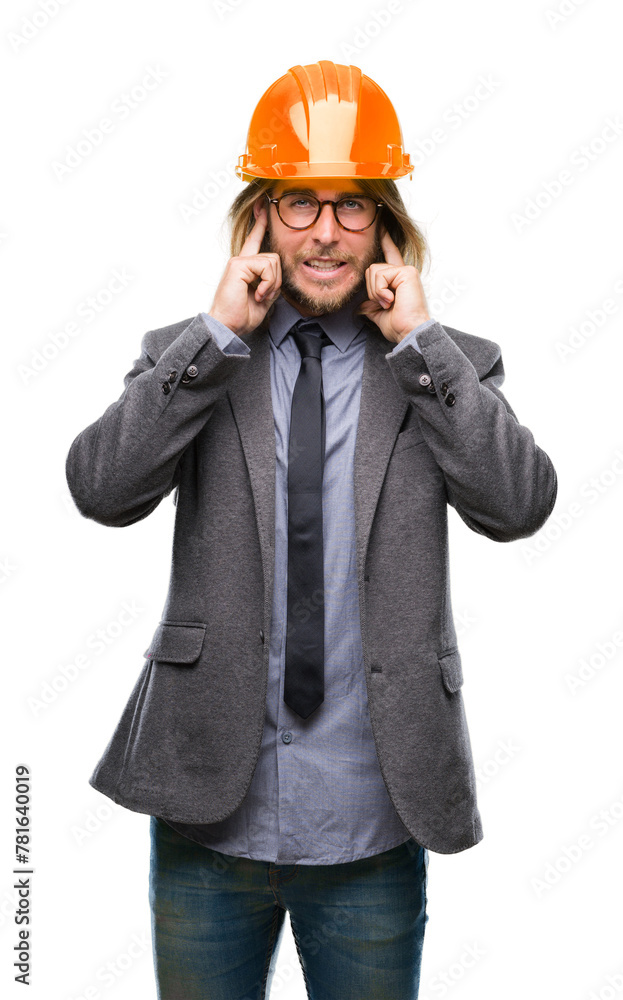 Young handsome architec man with long hair wearing safety helmet over isolated background covering ears with fingers with annoyed expression for the noise of loud music. Deaf concept. Young handsome architec man with long hair wearing safety helmet over isolated background covering ears with fingers with annoyed expression for the noise of loud music. Deaf concept.