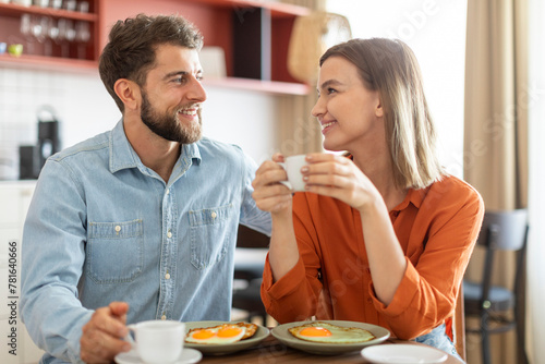 Cheerful european woman holding cup of coffee, listening and looking at her boyfriend, loving couple enjoying time together at cafe