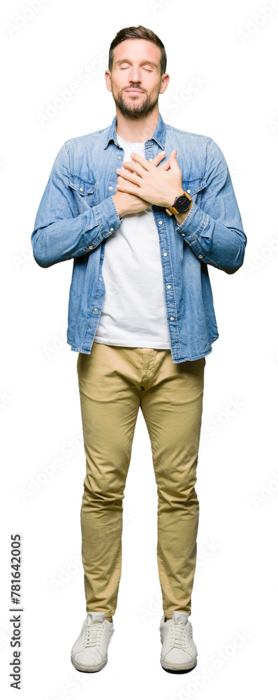 Handsome man with blue eyes and beard wearing denim jacket smiling with hands on chest with closed eyes and grateful gesture on face. Health concept. Handsome man with blue eyes and beard wearing denim jacket smiling with hands on chest with closed eyes and grateful gesture on face. Health concept.