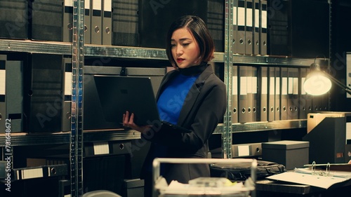 Obraz na plátně Detective evaluating old archived folders to organize all cases based on crimes, digitizes documents to preserve evidence on laptop