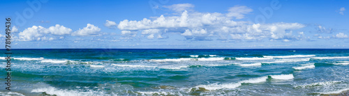 Panoramic unique bodies of cumulus thunderstorm clouds over ocean waters horizon line in blue sky background.