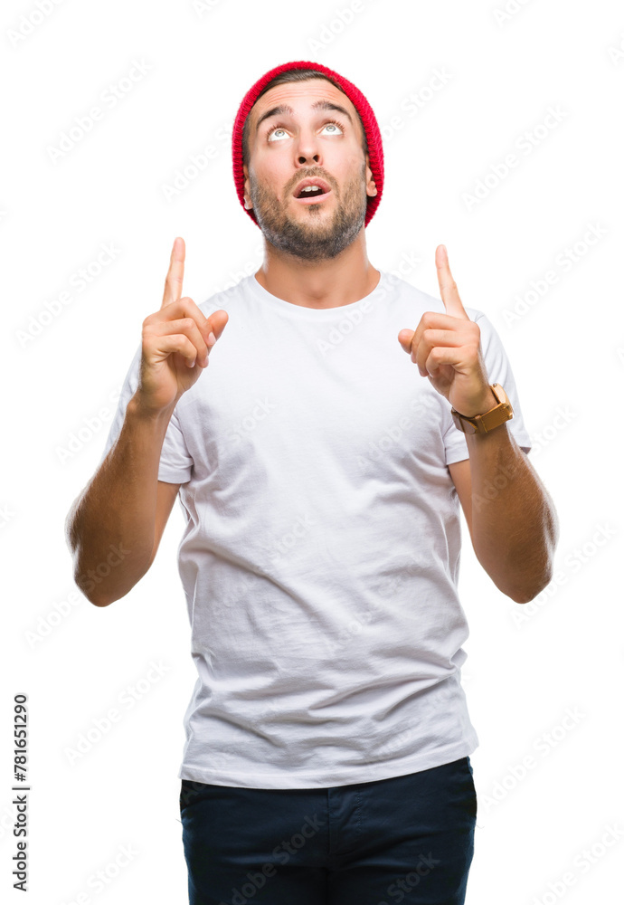 Young handsome man over isolated background amazed and surprised looking up and pointing with fingers and raised arms. Young handsome man over isolated background amazed and surprised looking up and pointing with fingers and raised arms.