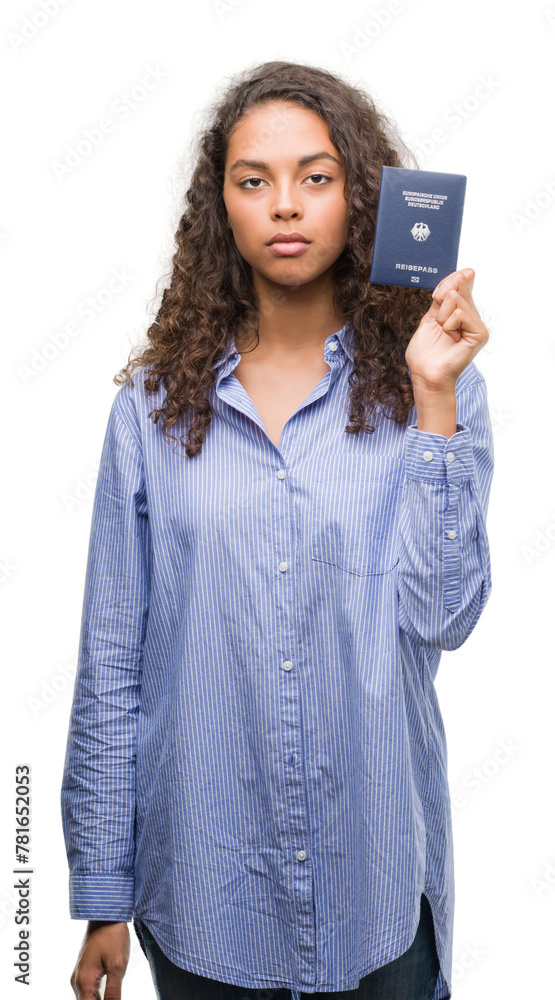 Young hispanic woman holding passport of Germany with a confident expression on smart face thinking serious Young hispanic woman holding passport of Germany with a confident expression on smart face thinking serious