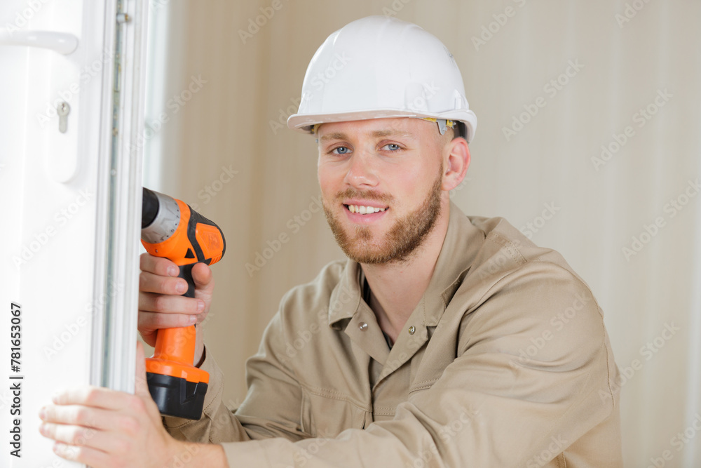 tradesman using cordless screwdriver to work on pvc door tradesman using cordless screwdriver to work on pvc door