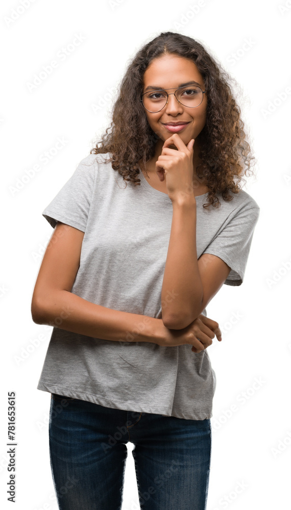 Beautiful young hispanic woman wearing glasses looking confident at the camera with smile with crossed arms and hand raised on chin. Thinking positive. Beautiful young hispanic woman wearing glasses looking confident at the camera with smile with crossed arms and hand raised on chin. Thinking positive.