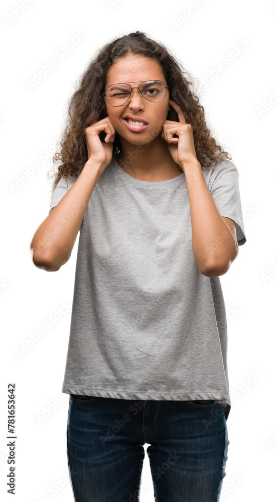 Beautiful young hispanic woman wearing glasses covering ears with fingers with annoyed expression for the noise of loud music. Deaf concept. Beautiful young hispanic woman wearing glasses covering ears with fingers with annoyed expression for the noise of loud music. Deaf concept.