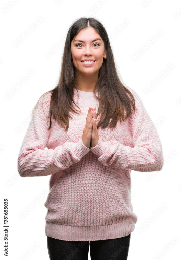Young beautiful hispanic woman wearing a sweater praying with hands together asking for forgiveness smiling confident. Young beautiful hispanic woman wearing a sweater praying with hands together asking for forgiveness smiling confident.