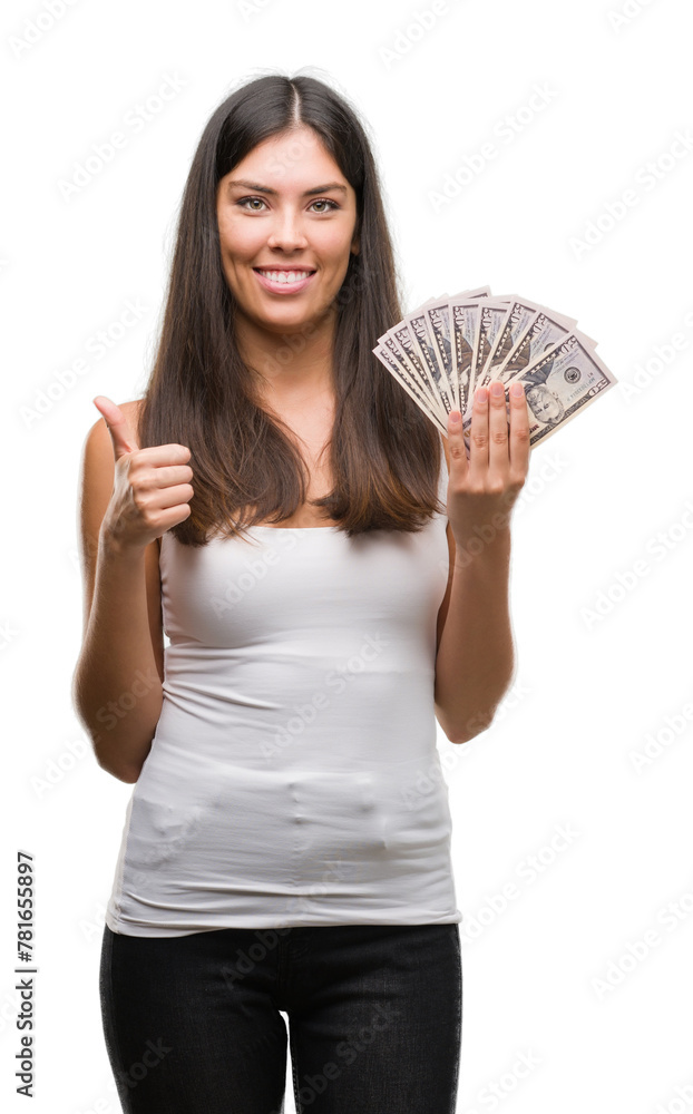 Young hispanic woman holding dollars happy with big smile doing ok sign, thumb up with fingers, excellent sign Young hispanic woman holding dollars happy with big smile doing ok sign, thumb up with fingers, excellent sign