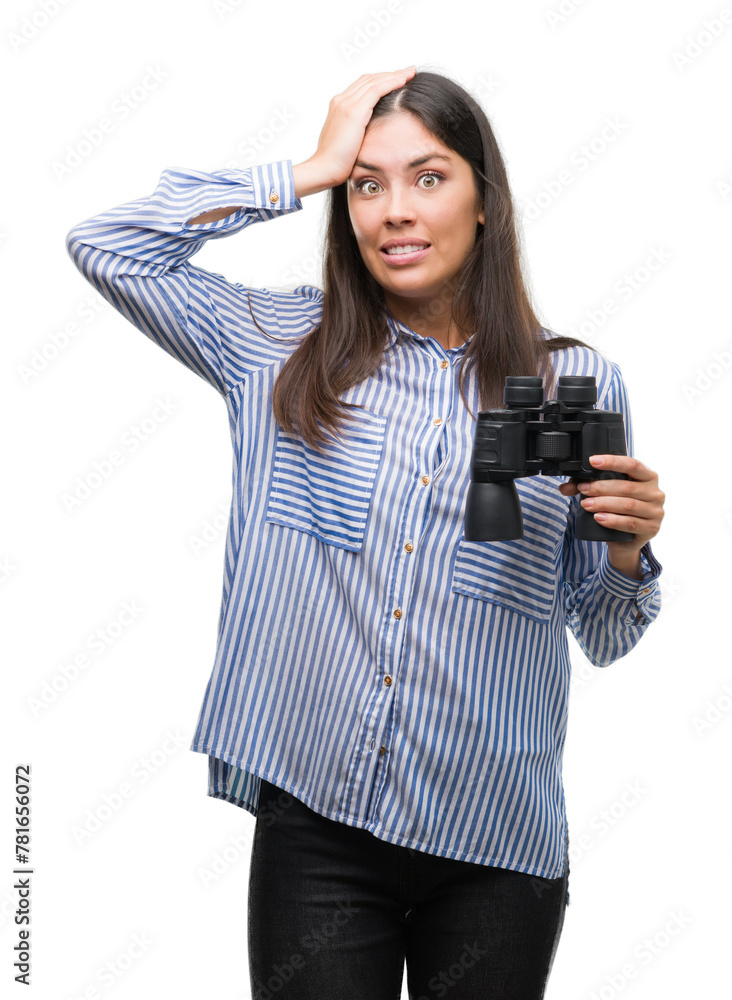 Young hispanic woman holding binoculars stressed with hand on head, shocked with shame and surprise face, angry and frustrated. Fear and upset for mistake. Young hispanic woman holding binoculars stressed with hand on head, shocked with shame and surprise face, angry and frustrated. Fear and upset for mistake.