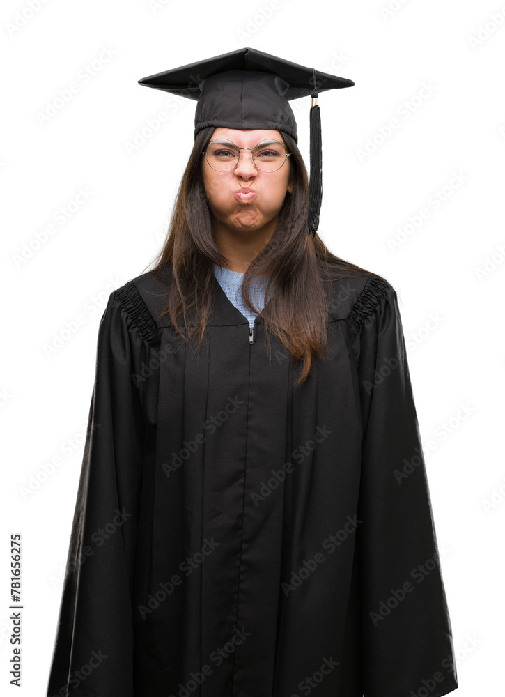 Young hispanic woman wearing graduated cap and uniform puffing cheeks with funny face. Mouth inflated with air, crazy expression. Young hispanic woman wearing graduated cap and uniform puffing cheeks with funny face. Mouth inflated with air, crazy expression.