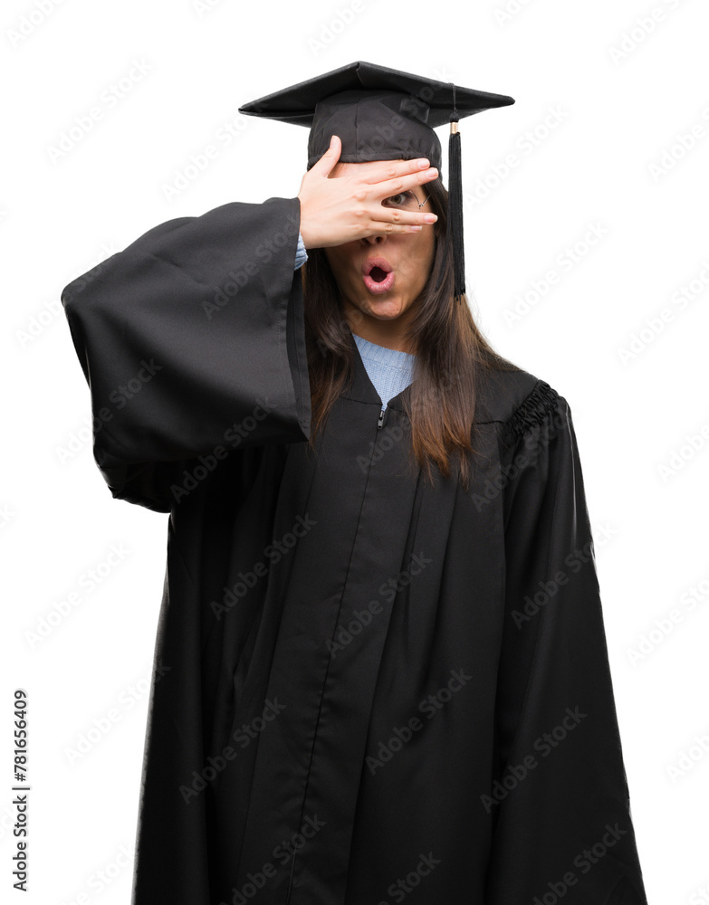 Young hispanic woman wearing graduated cap and uniform peeking in shock covering face and eyes with hand, looking through fingers with embarrassed expression. Young hispanic woman wearing graduated cap and uniform peeking in shock covering face and eyes with hand, looking through fingers with embarrassed expression.