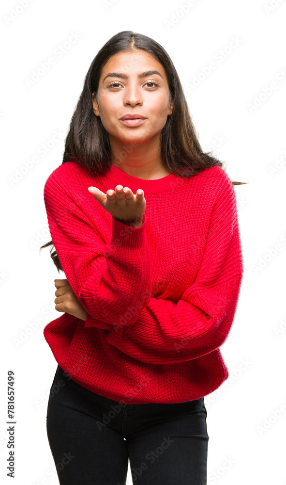 Young beautiful arab woman wearing winter sweater over isolated background looking at the camera blowing a kiss with hand on air being lovely and sexy. Love expression. Young beautiful arab woman wearing winter sweater over isolated background looking at the camera blowing a kiss with hand on air being lovely and sexy. Love expression.