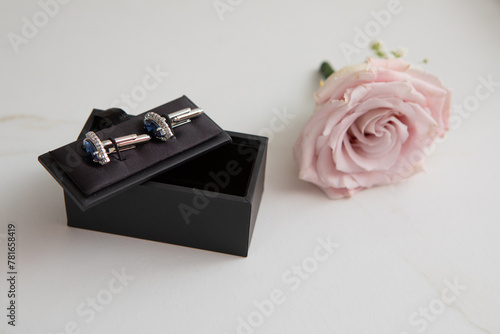 elegant cufflinks in box with pink rose boutonniere on side