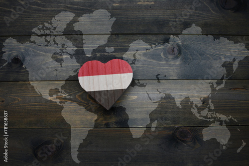 wooden heart with national flag of yemen near world map on the wooden background.