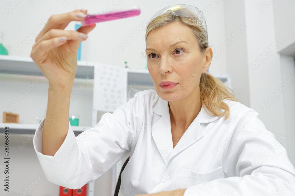 mature minded woman looking at a test tube - obrazy, fototapety, plakaty 
