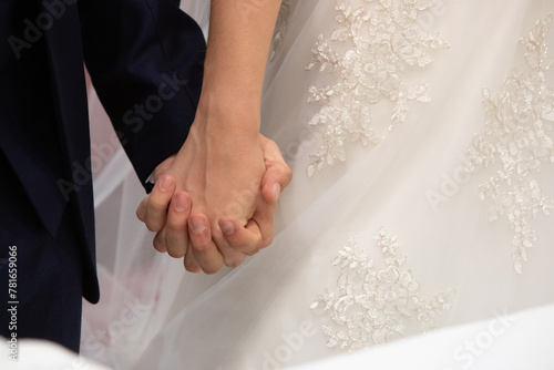 newlyweds holding hands showcasing rings and wedding attire