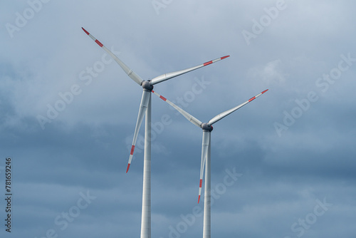 Two wind turbines against the cloudy sky