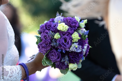 bride's hand delicately holding a bouquet of purple and lilac flowers