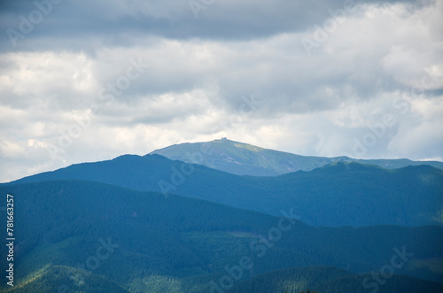 A serene and captivating landscape showcasing the majestic beauty of a mountain range with highest peak Pip Ivan with observatory enveloped in the soft embrace of cloudy skies. Carpathians, Ukraine