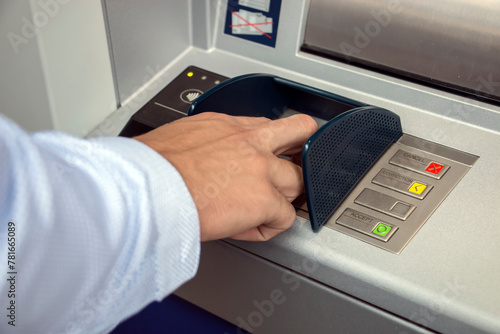 ATM machine and close-up man hand pushing on the pin button. Hand entering personal identification number on ATM dial panel  photo