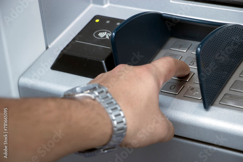 ATM machine and close-up man hand pushing on the pin button. Hand entering personal identification number on ATM dial panel  photo
