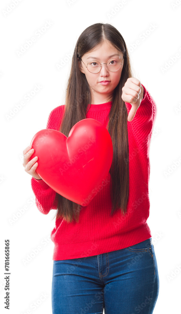 Young Chinese woman wearing graduate uniform red heart with angry face, negative sign showing dislike with thumbs down, rejection concept Young Chinese woman wearing graduate uniform red heart with angry face, negative sign showing dislike with thumbs down, rejection concept