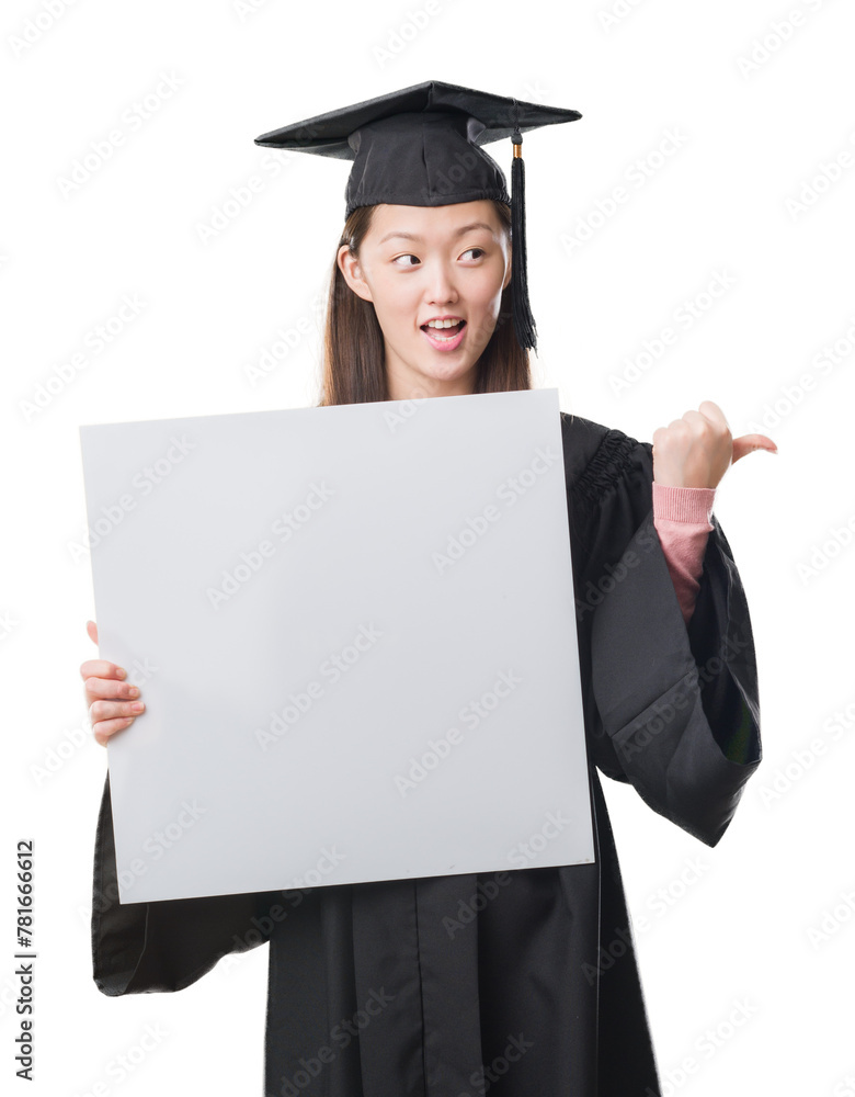 Young Chinese woman wearing graduate uniform holding banner pointing and showing with thumb up to the side with happy face smiling Young Chinese woman wearing graduate uniform holding banner pointing and showing with thumb up to the side with happy face smiling