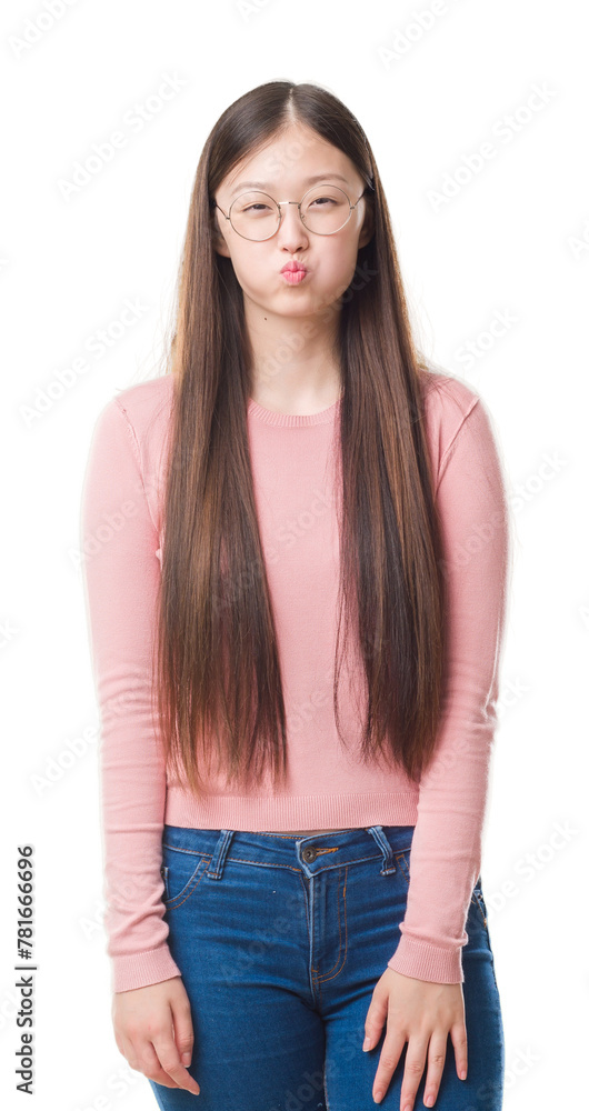 Obraz premium Young Chinese woman over isolated background wearing glasses puffing cheeks with funny face. Mouth inflated with air, crazy expression.