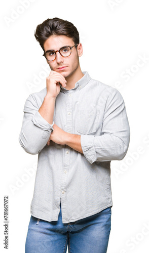 Young handsome man wearing glasses over isolated background with hand on chin thinking about question, pensive expression. Smiling with thoughtful face. Doubt concept. © Krakenimages.com