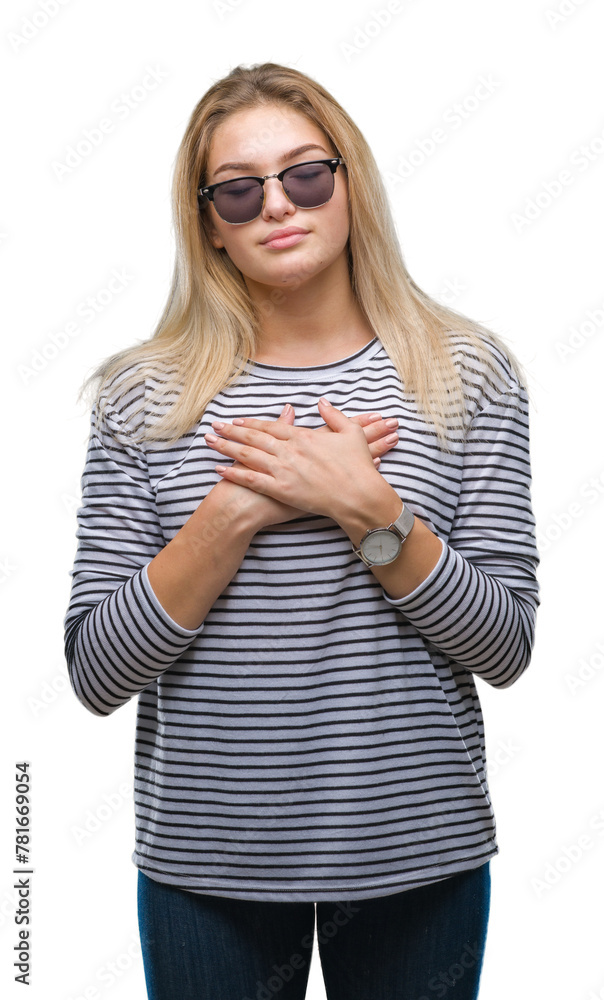 Fototapeta premium Young caucasian woman wearing sunglasses over isolated background smiling with hands on chest with closed eyes and grateful gesture on face. Health concept.