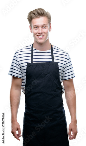 Young handsome blond man wearing apron with a happy face standing and smiling with a confident smile showing teeth