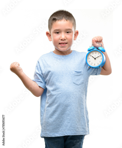 Little child holding alarm clock screaming proud and celebrating victory and success very excited, cheering emotion