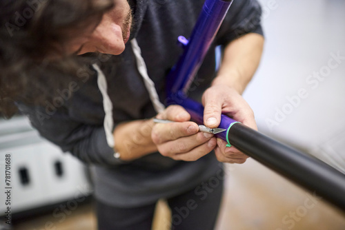 Latin young man working on a custom bike frame painting design, a creative and technical handcrafted process.