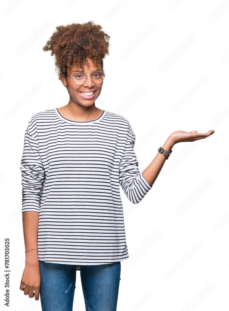 Beautiful young african american woman wearing glasses over isolated background smiling cheerful presenting and pointing with palm of hand looking at the camera. Beautiful young african american woman wearing glasses over isolated background smiling cheerful presenting and pointing with palm of hand looking at the camera.