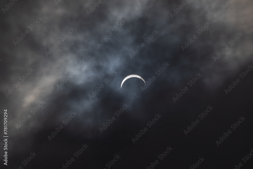 Partial solar eclipse - moon covers sun, dark clouds, celestial drama - crescent sun - atmospheric mood. Taken in Toronto, Canada. Partial solar eclipse - moon covers sun, dark clouds, celestial drama - crescent sun - atmospheric mood. Taken in Toronto, Canada.