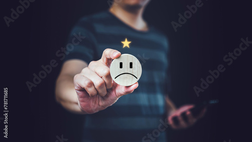 Satisfaction concept, Man holding circular wooden board with sad face icon.