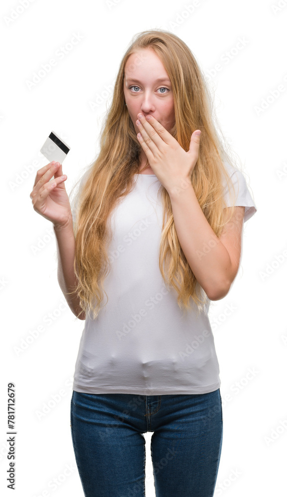 Blonde teenager woman holding credit card cover mouth with hand shocked with shame for mistake, expression of fear, scared in silence, secret concept Blonde teenager woman holding credit card cover mouth with hand shocked with shame for mistake, expression of fear, scared in silence, secret concept