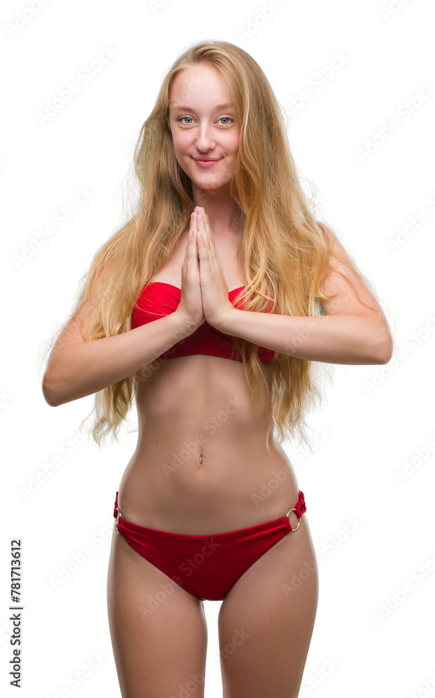 Blonde teenager woman wearing red bikini praying with hands together asking for forgiveness smiling confident. Blonde teenager woman wearing red bikini praying with hands together asking for forgiveness smiling confident.