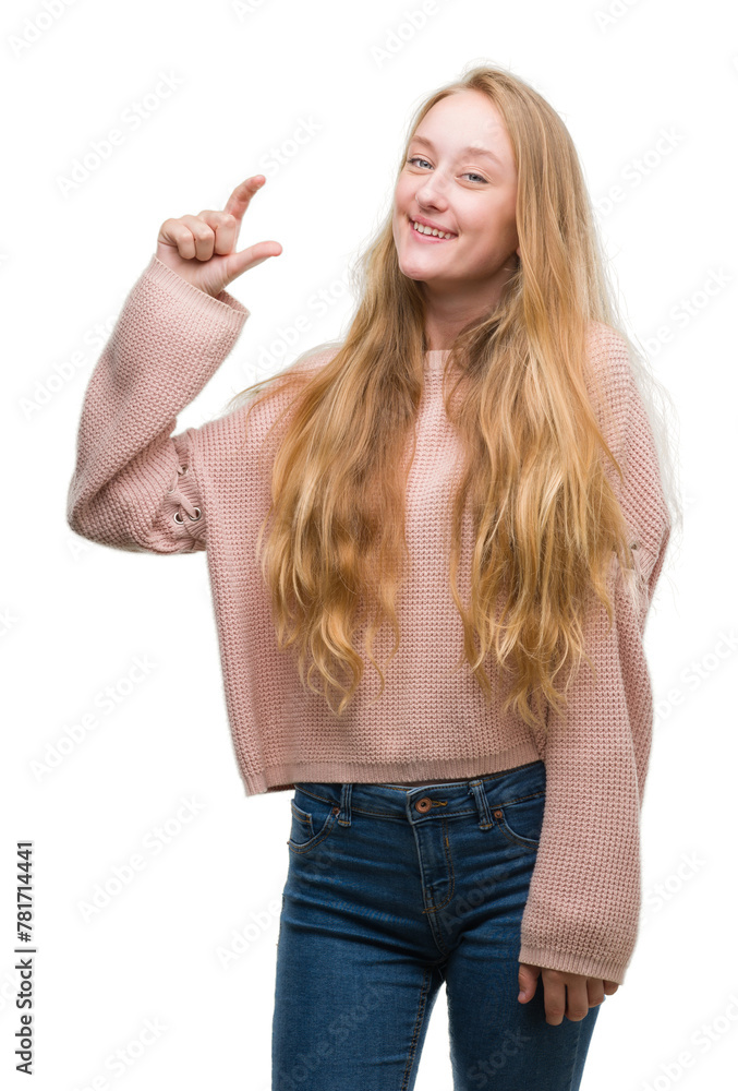 Blonde teenager woman wearing pink sweater smiling and confident gesturing with hand doing size sign with fingers while looking and the camera. Measure concept. Blonde teenager woman wearing pink sweater smiling and confident gesturing with hand doing size sign with fingers while looking and the camera. Measure concept.