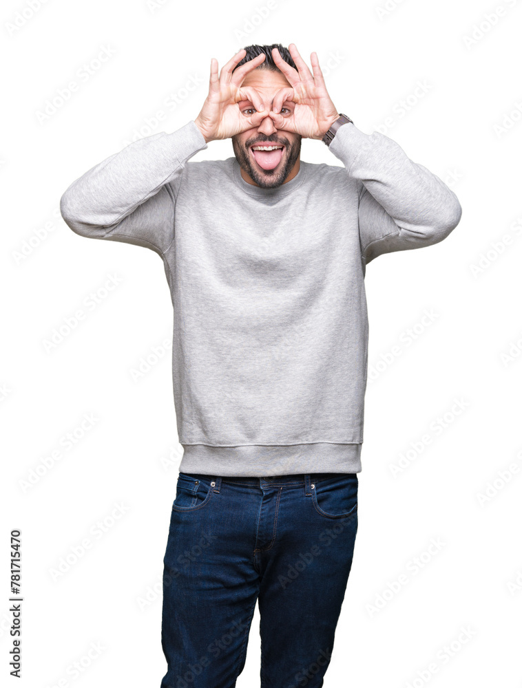 Fototapeta premium Young handsome man wearing sweatshirt over isolated background doing ok gesture like binoculars sticking tongue out, eyes looking through fingers. Crazy expression.