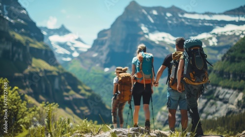 A group of hikers pause on a rocky mountain trail taking in the breathtaking vista of lush green valleys and snowy peaks. faces . . © Justlight