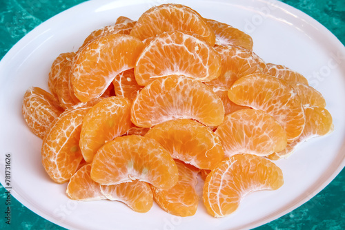 Tangerine slices or mandarin orange fruit  in white plate close up background