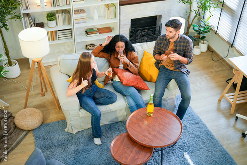 Obraz na płótnie Friends enjoy a relaxed gathering at home, casually chatting and sipping drinks in a cozy living room setting