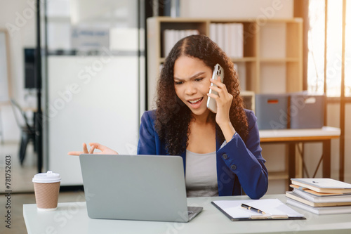 Confident business expert attractive smiling young woman typing laptop and holding digital tablet on desk © laddawan