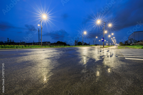 Asphalt road and bright street lights scenery at night after rain