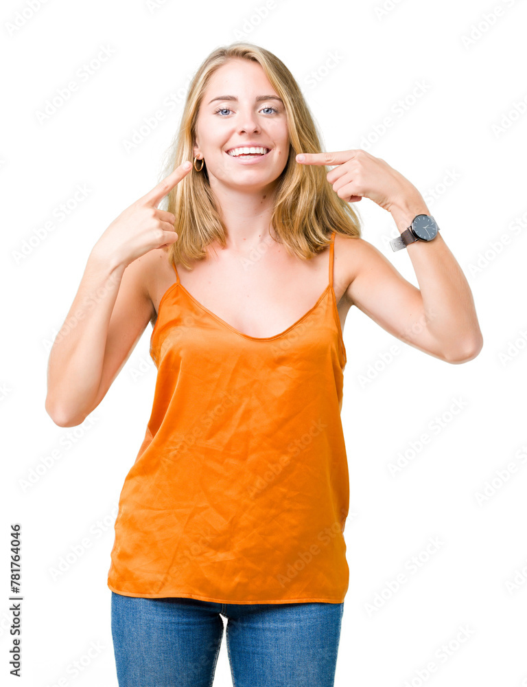 Beautiful young woman wearing orange shirt over isolated background smiling confident showing and pointing with fingers teeth and mouth. Health concept. Beautiful young woman wearing orange shirt over isolated background smiling confident showing and pointing with fingers teeth and mouth. Health concept.