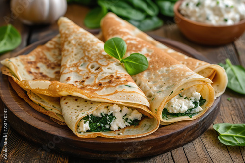 Savory crepes with spinach and ricotta on a white plate © lermont51