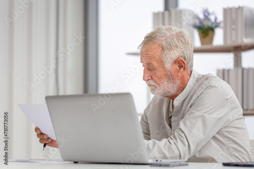 Worried senior man checking their bills, retired elderly old family reading documents, Mature man in living room with laptop