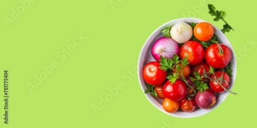 Top view of a bowl full of fresh vegetables, tomatoes, parsley, and onions isolated on light green background.