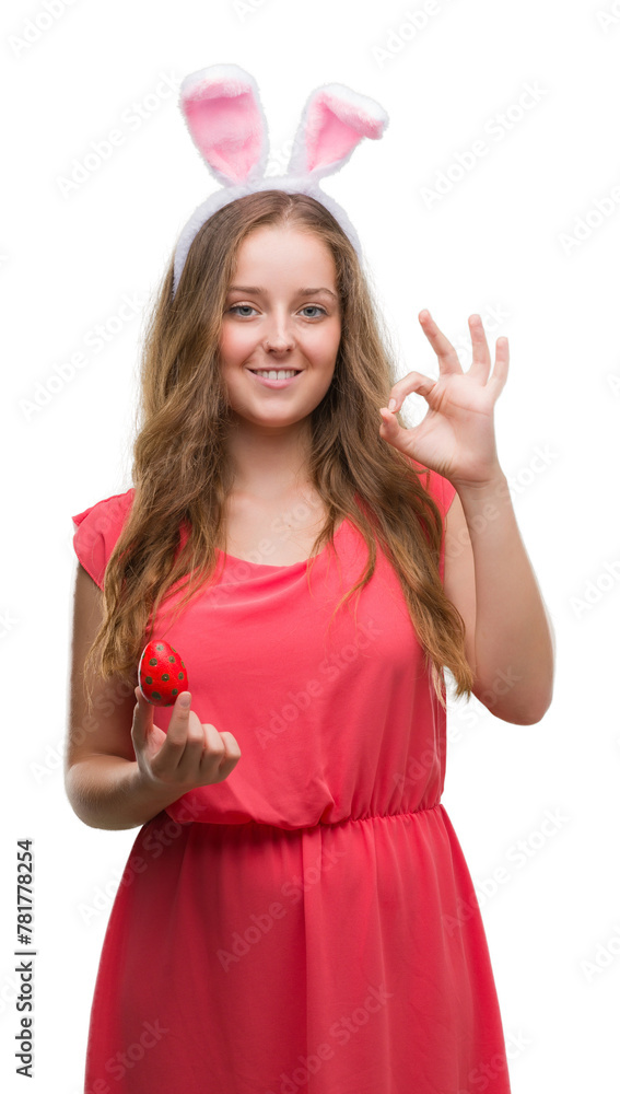Young blonde woman wearing easter bunny ears doing ok sign with fingers, excellent symbol Young blonde woman wearing easter bunny ears doing ok sign with fingers, excellent symbol